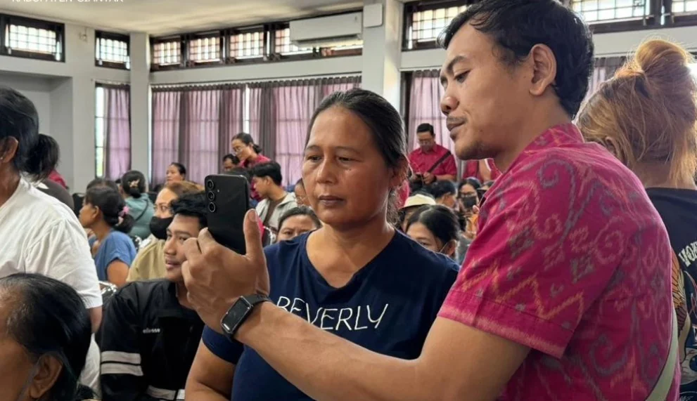 Pendamping membantu peserta menggunakan ponsel pada uji coba bantuan sosial digital di Blahbatuh